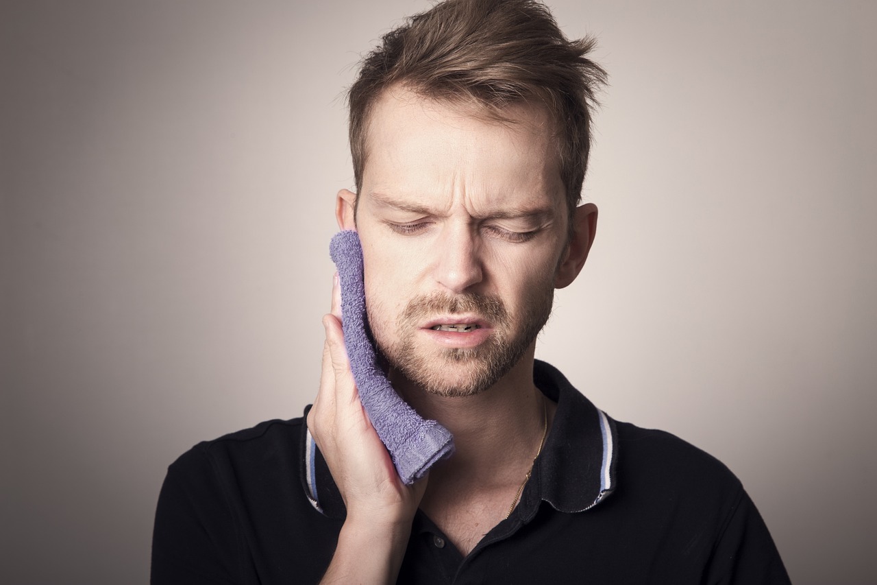 man holding blue rag to jaw for tooth pain